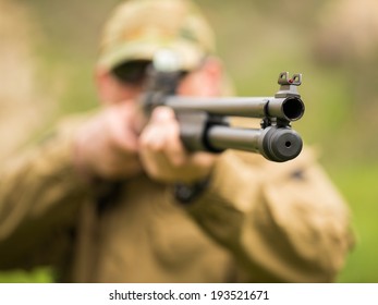 Man In Camouflage With A Shotgun Aiming At A Target. Focus On Hole, Small DOF