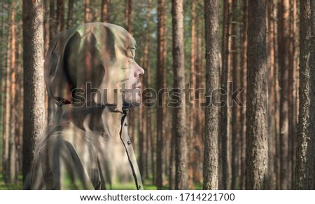 A man in a camouflage suit in the forest. Side view. Copy space.