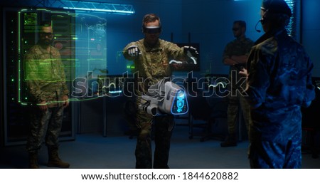 Man in camouflage uniform and goggles using controllers to operate modern military UAV
