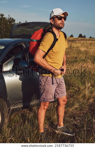 Man camping and hiking in nature,\
unpacking from car outdoors, recreation and\
hobbies.
