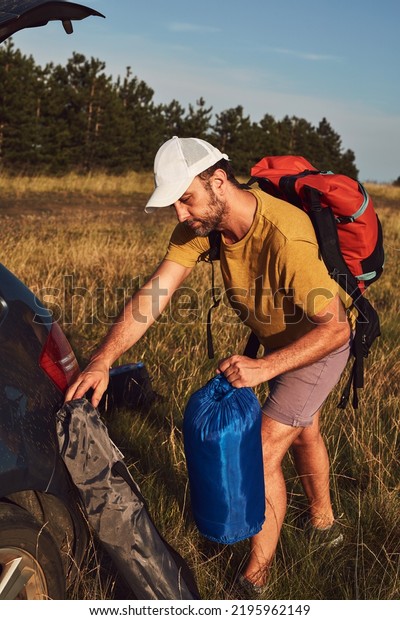 Man camping in nature, unpacking\
and packing small tent outdoors, recreation and\
hobbies.