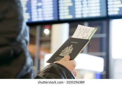 A Man With A Canadian Passport And Boarding Pass Looks At The Airport Departure