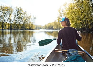 Man, canoeing and lake rowing in nature for morning adventure or exercise, exploring or island. Male person, back and Colorado traveling for outdoor hobby with boat at camp site, forest or nature