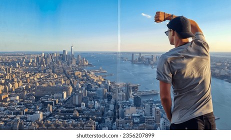 A man in a cap standing at the observatory deck of The Edge with captivating aerial view of New York City skyline over the Hudson River during the dusk. Endless rows of tall buildings. Travelling - Powered by Shutterstock