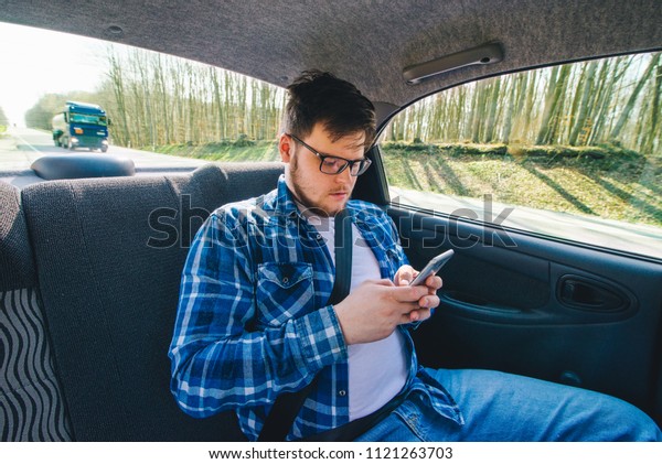 man at\
car backseat using phone. car travel\
concept