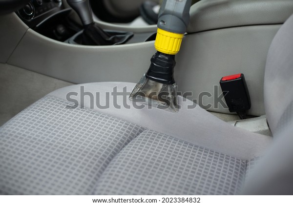 Man car detailing studio worker cleaning car\
textile upholstery