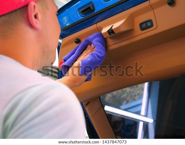 The man in the car dries from inside\
all parts of the car using a rag and a compressed air gun. Concept\
of: New car, Drying, On the style, Luxury\
class.