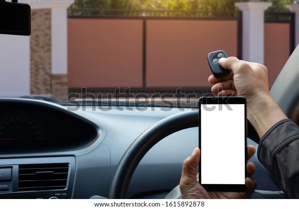 Man\
in car, hand opening the auto door by using remote control ,hand\
holding mobile smart phone with empty white screen while driving \
.Home security system and mobile technology\
concept.