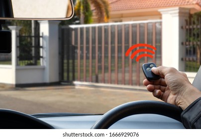 Man in car, hand using remote control to open the automatic gate. The auto electric door, home gate garage remote control and security system  concept. 