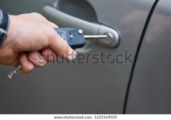 Man with car key. Opening\
car door.