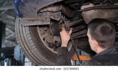 Man Car Mechanic With Tools Inspects The Car's Running System. Worker In Uniform. Defective Car