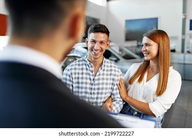 Man Car Salesman Telling About The Features Of The New Car To The Couple