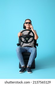 Man In Car Seat And With Steering Wheel Talking By Phone On Color Background