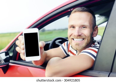 Man in car showing smart phone display smiling happy. Focus on model. Toned photo.