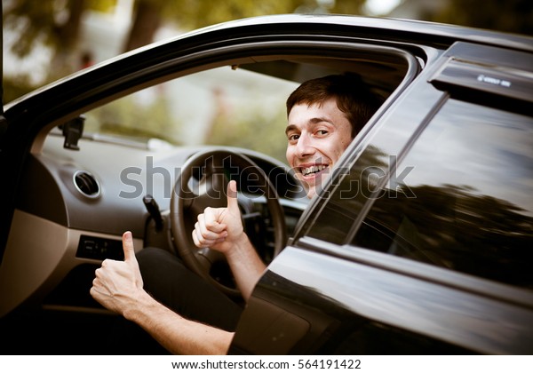 The man in the car\
smiles and shows cool
