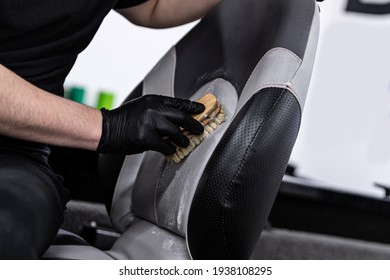 Man car wash worker cleaning leather boat seat with brush