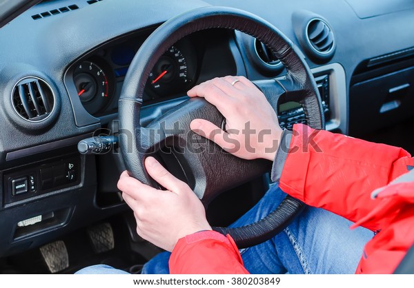 The man at a car wheel. Hands of the man lie\
on a wheel. The man presses a signal on a wheel to the car.\
Management of transport.