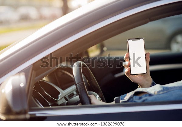 man in the car. Young\
business man with phone in car. Man holding smartphone with blank\
screen .