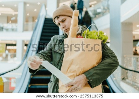 Man carefully reviewing receipts while carrying fresh produce, highlighting inflation impact, prioritizing health, and tracking household budget in public space