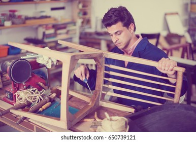 Man Carpenter With Screwdriver In Hand Working In Furniture Repair Workshop