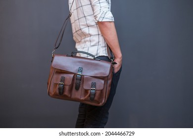 Man carries brown leather messenger bag in the hand. Unisex bag for sale. - Powered by Shutterstock