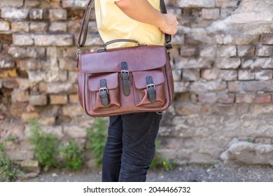 Man carries brown leather messenger bag in the hand. Unisex bag for sale. - Powered by Shutterstock