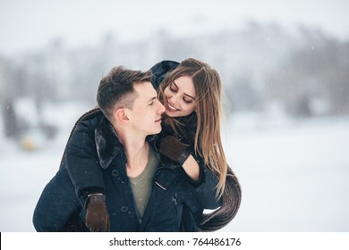 man carries his girlfriend on the back in the park, in winter holidays
