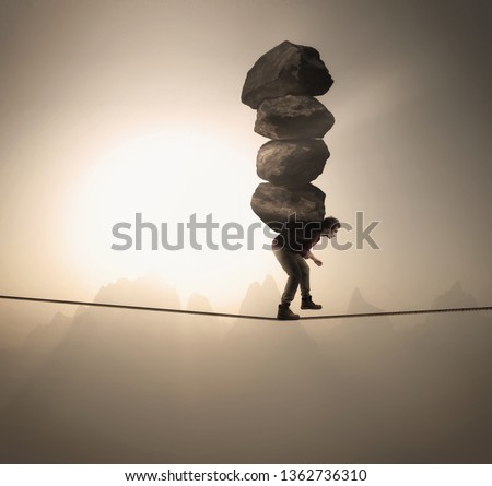 Man carries a stack of big rocks while balancing on a rope at high altitude .