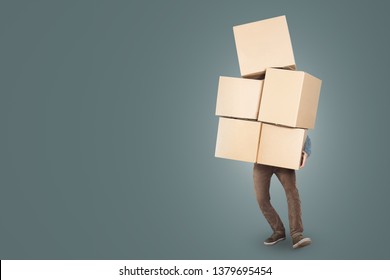 Un hombre lleva una gran pila de cajas de cartón en sus brazos