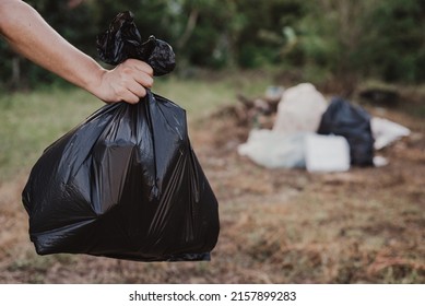 A Man Is Carrying A Garbage Bag In A Black Bag. Go To The Landfill.