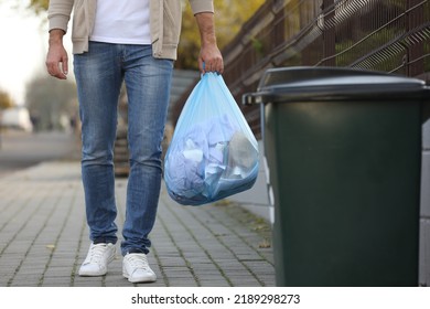 Man Carrying Garbage Bag To Recycling Bin Outdoors, Closeup