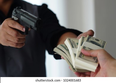 Man Carrying A Gun To Rob The Money.  The Bad Man Hold Gun To Rob In The Bank. Thief Or Robber In Black Shirt  With Gun Threatens Man Or Woman For Steal Money On Street, Dangerous Criminal In The City