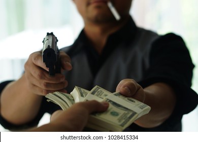 Man Carrying A Gun To Rob The Money.  The Bad Man Hold Gun To Rob In The Bank. Thief Or Robber In Black Shirt  With Gun Threatens Man Or Woman For Steal Money On Street, Dangerous Criminal In The City