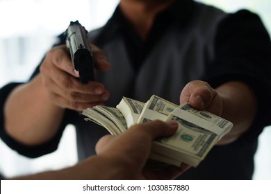 Man Carrying A Gun To Rob The Money.  The Bad Man Hold Gun To Rob In The Bank. Thief Or Robber In Black Shirt  With Gun Threatens Man Or Woman For Steal Money On Street, Dangerous Criminal In The City