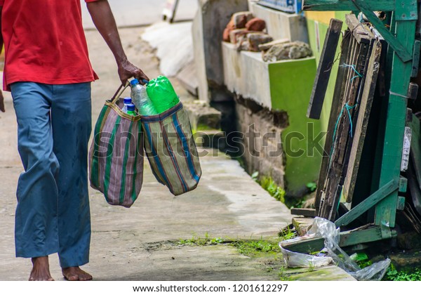 Man carrying\
Plastic bottle in bag on a road for recycling. Stop using plastic.\
Beat plastic pollution . Save the earth and environment concept.\
World Environment Day 2018.\
