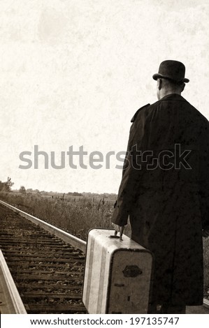 A man carrying a suitcase is walking down a railroad track.