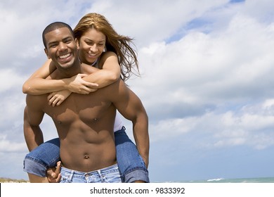 Man carrying woman on his back on a beach.