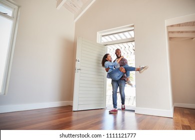 Man Carrying Woman Over Threshold Of Doorway In New Home