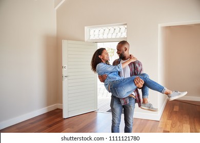 Man Carrying Woman Over Threshold Of Doorway In New Home