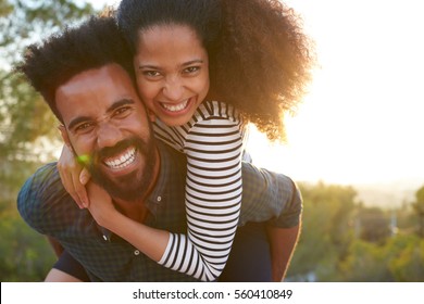 Man carrying young woman on his shoulders, looking to camera - Powered by Shutterstock