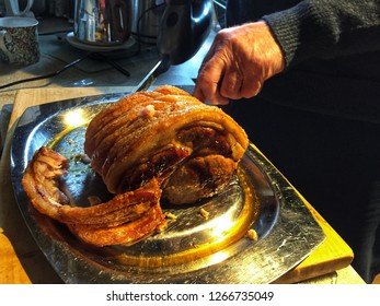 A Man Carving A Joint Of Roast Pork With An Electric Carving Knife.