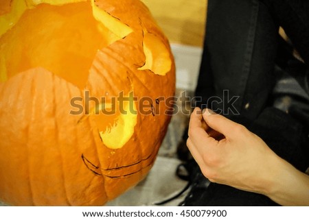 Man carving a pumpkin shaped as a cat for Halloween