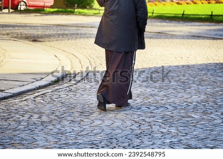 A man in a cassock walks down the street - a priest.