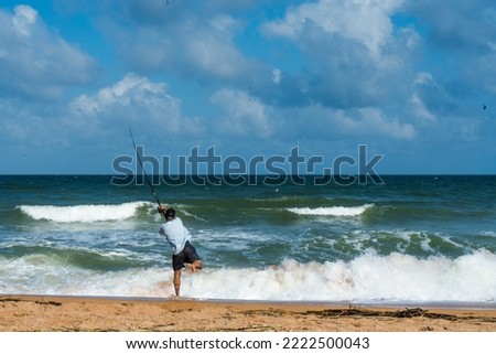 Man casting fishing pole on a beach of Atlantic Ocean on the coast of Florida