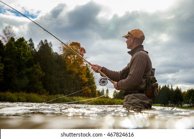 A man casts his fly rod into a river during the autumn