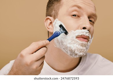 A man in casual attire carefully shaves his face with a razor. - Powered by Shutterstock