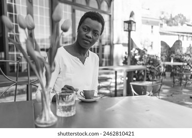 Man in casual attire enjoying a drink from a red coffee cup in an outdoor cafe scene - Powered by Shutterstock