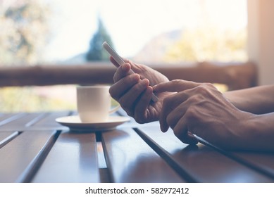 Man in casual wear relax using mobile smart phone and drinking hot coffee at coffee shop in vintage style, browsing on phone, internet of things IoT concept - Shutterstock ID 582972412