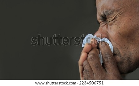 man catching the cold and flu man blowing nose after catching a cold with grey background with people stock photo