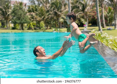 Man Catching His Son Who Is Jumping Into The Pool